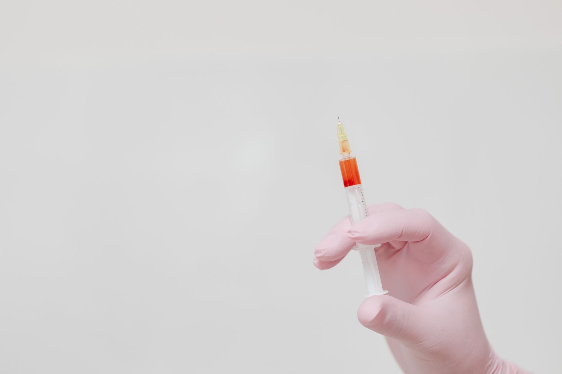 Gloved hands preparing a nutrient injection in a clinical setting